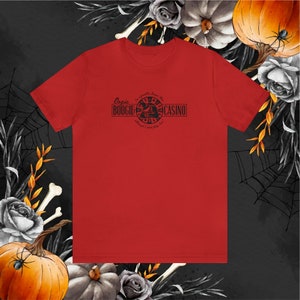 Pu&ograve; includere: Maglietta rossa con la scritta nera "Oogie Boogie Casino". Il design include una ruota della roulette e la frase "I'm a gambling Boogie man, although I don't play fair!". Decorazioni a tema Halloween.