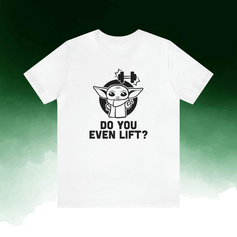 K&ouml;nnte beinhalten: Wei&szlig;es T-Shirt mit einem schwarzen Aufdruck eines Zeichentrickcharakters, einer Hantel und dem Text "DO YOU EVEN LIFT?". Die Figur zeigt das Friedenszeichen. Das Shirt besteht aus einem weichen, bequemen Material.