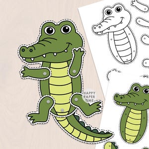 Könnte beinhalten: Ein Papierbastelset mit einem grünen Krokodil mit hellgelbem Bauch. Das zusammengebaute Krokodil hat bewegliche Gliedmaßen, die mit silbernen Nieten befestigt sind. Zwei weitere Blätter zeigen die Krokodilteile in Farbe und als Schwarz-Weiß-Umrisse.