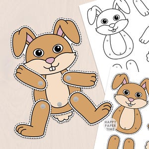 Puede incluir: Un kit de manualidades en papel con un conejo marrón de extremidades móviles unidas por cierres plateados. El kit incluye un conejo ensamblado y dos hojas impresas con piezas en blanco y negro o a color y el texto Happy Paper Time.