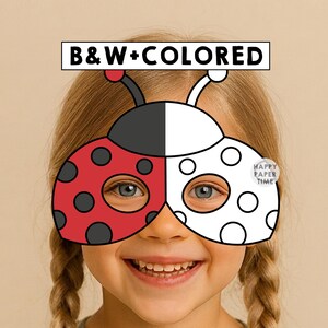 Puede incluir: Una máscara de mariquita con un diseño dividido, un lado en rojo con puntos negros y el otro lado en blanco con contornos negros. La máscara incluye dos antenas y un letrero rectangular en la parte superior con el texto B&W+COLORED en negro.