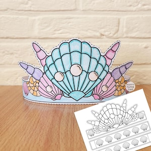 May include: A paper crown featuring a large central blue seashell with three white pearls, flanked by smaller pink, purple, and orange seashells. A separate black and white printable template sheet with shell outlines is positioned in the foreground.
