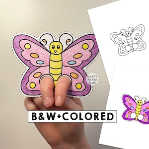 May include: A paper butterfly finger puppet with a yellow body and pink wings featuring purple edges and multi-colored spots. The butterfly has two circular cutouts at the bottom for fingers. Additional black and white and colored butterfly templates are visible.