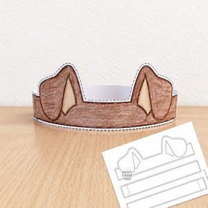 May include: A brown paper dog ear headband with a dashed cutting line along the edges. Beside it lies a flat, white printable template sheet featuring the same dog ear design and the text Happy Paper Time, ready for assembly and coloring.