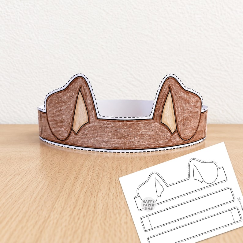May include: A brown paper dog ear headband with a dashed cutting line along the edges. Beside it lies a flat, white printable template sheet featuring the same dog ear design and the text Happy Paper Time, ready for assembly and coloring.