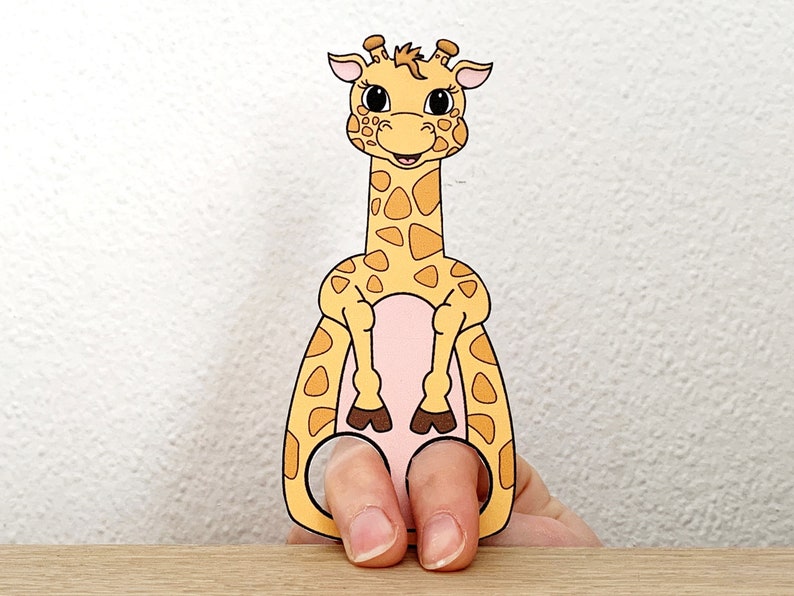 Puede incluir: Un t&iacute;tere de dedo de una jirafa con la barriga rosa y las pezu&ntilde;as marrones. La jirafa tiene un patr&oacute;n de manchas amarillas y naranjas.