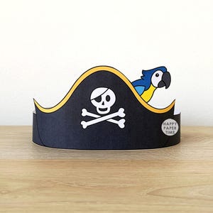 May include: A black pirate hat with a white skull and crossbones emblem, a yellow trim, and a blue and yellow parrot. The hat has the text "HAPPY PAPER TIME" on the side. Perfect for a costume or party.