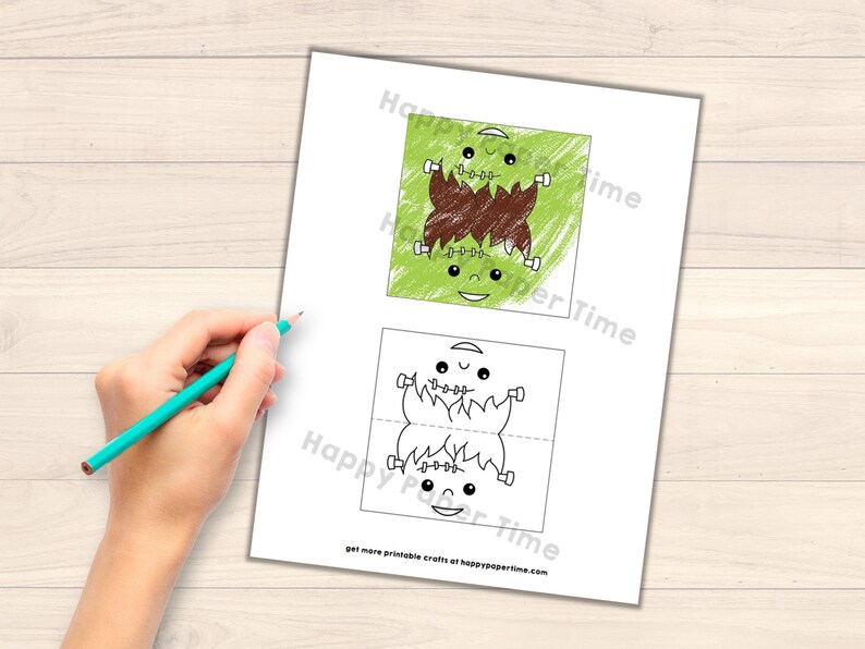 May include: Printable Frankenstein monster craft for kids. The craft is a foldable card with a green monster face on the front and a brown mouth on the back. The monster has two eyes, a smile, and stitches on its neck.