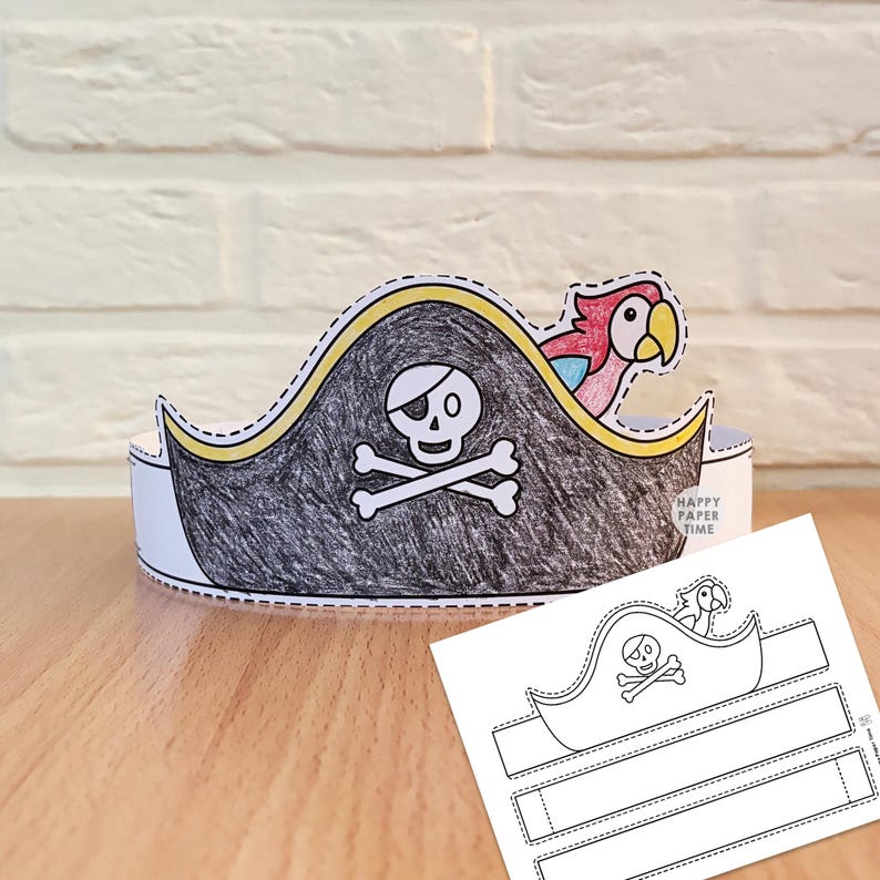 May include: A paper pirate hat craft featuring a black-colored hat with a white skull and crossbones emblem and a colorful parrot. The hat includes a yellow trim and is displayed alongside a flat, uncolored paper template with the text HAPPY PAPER TIME.