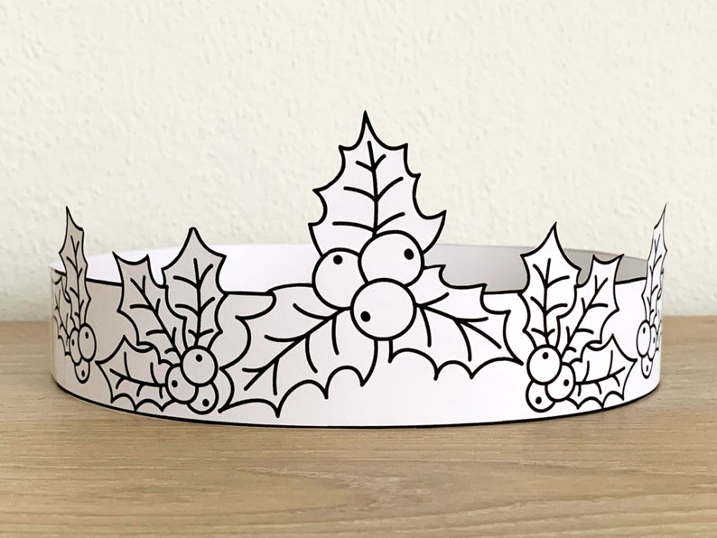 May include: A black and white printable paper crown with holly leaves and berries. The crown is designed to be cut out and worn.