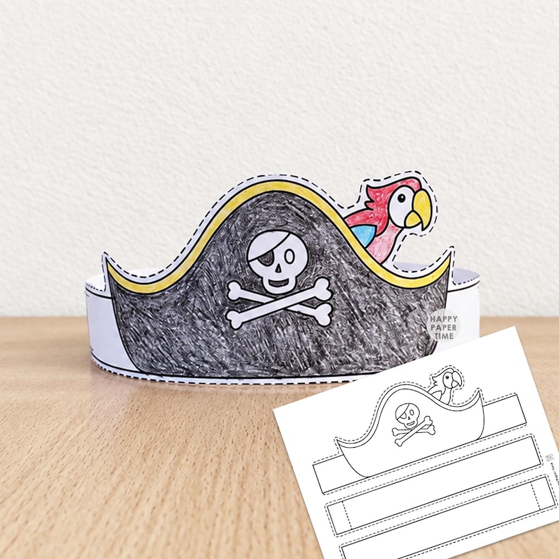 May include: A paper pirate hat craft featuring a black skull and crossbones design with a colourful parrot accent. The hat is coloured with black, yellow, red, and blue markers. A flat, uncoloured paper template with the same design is also visible.