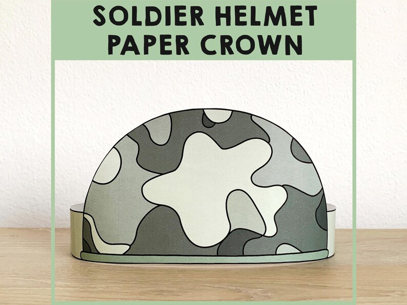 May include: A printable paper crown shaped like a camouflage soldier helmet. The crown is gray and green with a white star in the center.