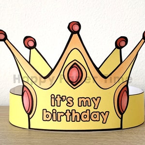 Puede incluir: Una corona de papel amarilla con detalles rojos y naranjas. La corona tiene las palabras "it's my birthday" escritas en ella.