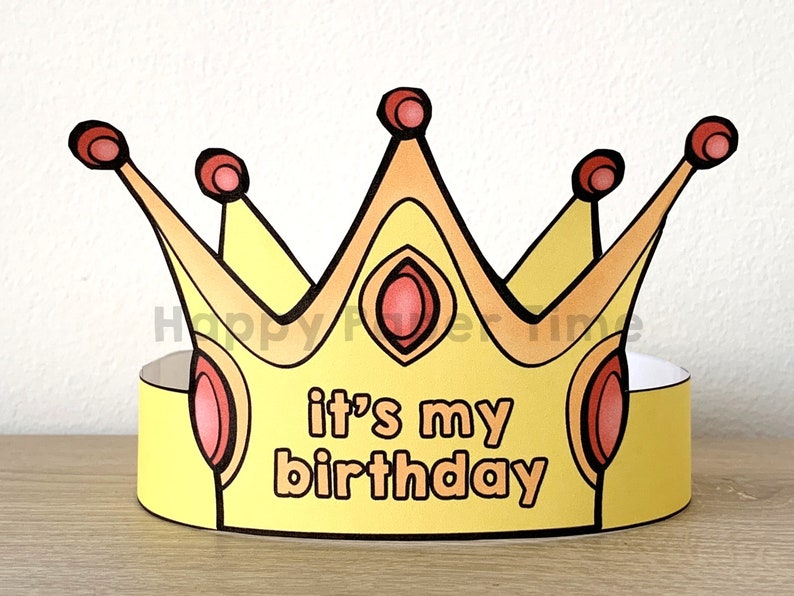 Puede incluir: Una corona de papel amarilla con detalles rojos y naranjas. La corona tiene las palabras "it's my birthday" escritas en ella.