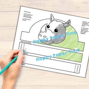 Op de afbeelding: Printbare neushoornkroon knutselmal. De mal bevat een neushoornkop in grijs en wit, een groene achtergrond en instructies voor montage. De tekst "Happy Paper Time" staat op de mal gedrukt.