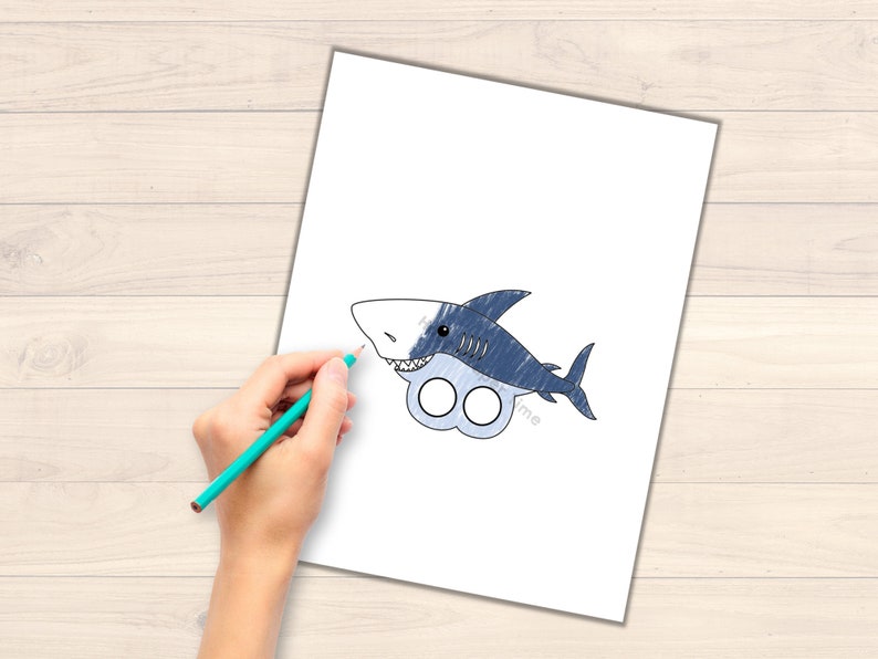 May include: A printable paper craft of a blue and white shark with finger holes for a puppet. The shark has a toothy grin and is ready to be colored in.