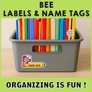 May include: A gray storage bin filled with colorful books and labels. The bin has a butterfly and pencil sticker that says "read me." The text "BEE LABELS & NAME TAGS" and "ORGANIZING IS FUN!" are also visible.