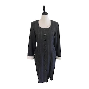 May include: A grey pinstripe dress with a white collar and button fastening. The dress has long sleeves and two pockets.