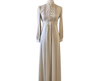 May include: A long-sleeved, beige maxi dress with a high collar and button detailing. The dress has a fitted bodice and a flowing skirt.