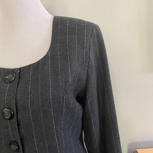 May include: A black and white striped blazer with a square neckline and button closure. The blazer is made of a soft, textured fabric.