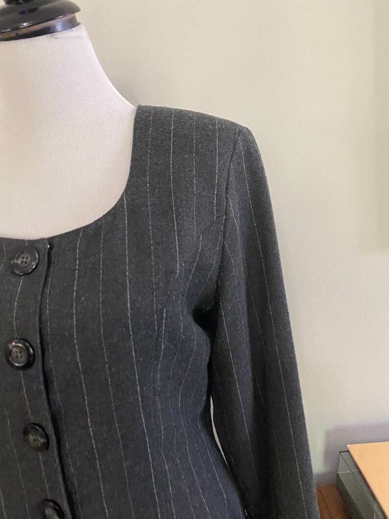 May include: A black and white striped blazer with a square neckline and button closure. The blazer is made of a soft, textured fabric.
