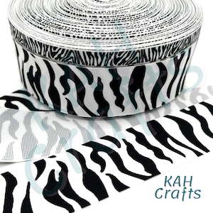 Puede incluir: Cinta de estampado de cebra en blanco y negro. La cinta está enrollada y muestra el patrón en ambos lados. La cinta tiene 3,8 cm de ancho.