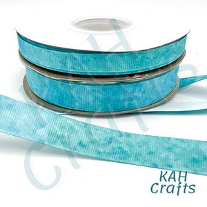 May include: Two spools of turquoise blue ribbon with a white marbled pattern. The ribbon is on a white background. KAH Crafts is printed in black text on the bottom right corner of the image.