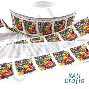 May include: White ribbon with a repeating pattern of a pink flamingo, the words "Float, Drink, Tan, Repeat", and a tropical scene. The ribbon is on a roll and unspooled, with the text "KAH Crafts" in the corner.