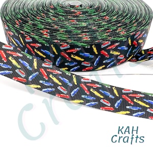 May include: Black ribbon with a repeating pattern of colorful cars. The ribbon is rolled up and the end is unfurled, showing the pattern. The ribbon is labeled "KAH Crafts".