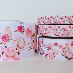 May include: Four rolls of white satin ribbon with a watercolor print of pink piglets wearing flowers and brown mud. The ribbon widths are 5/8 inch, 7/8 inch, 1.5 inches, and 3 inches.