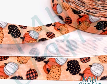 May include: Orange, black, and white patterned ribbon with a pumpkin design. The ribbon is rolled up and the back side is white.