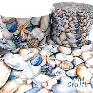 May include: A roll of white ribbon with a watercolor print of seashells, starfish, and pebbles. The ribbon is 1 inch wide and is perfect for crafting and decorating.