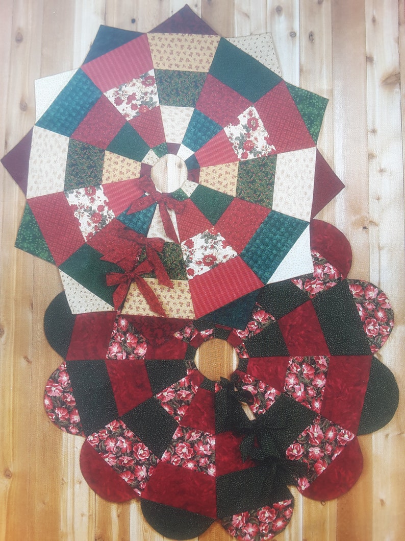 May include: Two quilted tree skirts with a floral design. The top skirt is a star shape with red, green, and cream-colored fabric. The bottom skirt is a flower shape with red and black fabric. Both have a center opening and a bow.
