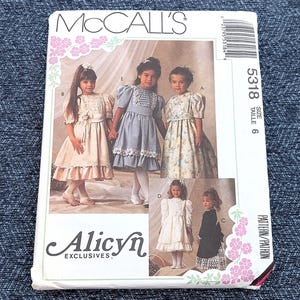 May include: McCall's sewing pattern featuring girls' dresses. The pattern cover displays illustrations of the dresses, including a cream-colored dress with lace trim and a black dress with a lace hem. The pattern size is 6.