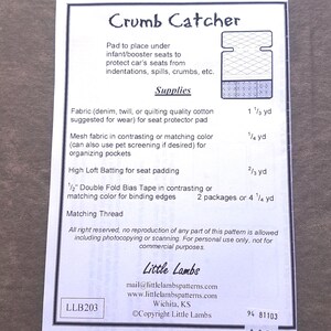 Pu&ograve; includere: Un foglio di carta bianco con il titolo "Crumb Catcher" e un diagramma di un proteggi-sedile. Il testo elenca i materiali necessari, tra cui tessuto, tessuto a rete, ovatta e sbieco. Il logo e le informazioni di contatto di Little Lambs sono in basso.