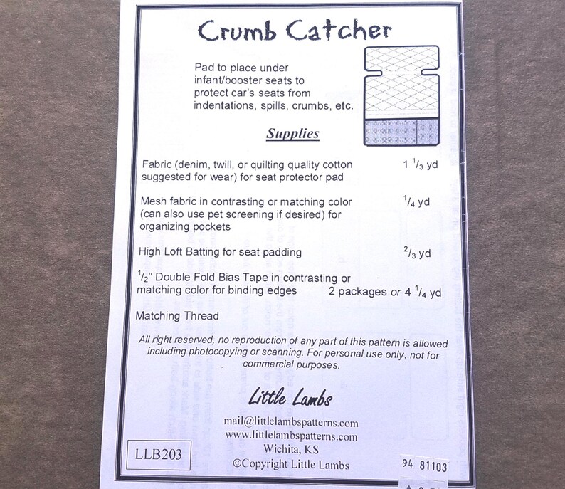 Pu&ograve; includere: Un foglio di carta bianco con il titolo "Crumb Catcher" e un diagramma di un proteggi-sedile. Il testo elenca i materiali necessari, tra cui tessuto, tessuto a rete, ovatta e sbieco. Il logo e le informazioni di contatto di Little Lambs sono in basso.