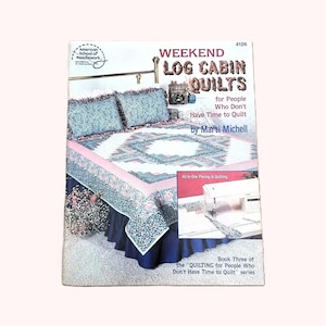 May include: A softcover instructional book titled Weekend Log Cabin Quilts for People Who Don't Have Time to Quilt by Marti Michell. The cover features a photograph of a bed with a floral quilt, a blue bed skirt, and a sewing machine inset.