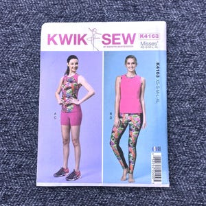 May include: A Kwik Sew sewing pattern, K4163, featuring a pink and patterned activewear set. The pattern includes a tank top and shorts, and a tank top and leggings. Sizes XS-XL are available. The cover has the text "KWIK SEW" and "Misses' XS-S-M-L-XL".