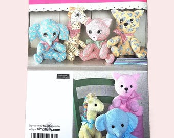 May include: Simplicity sewing pattern featuring stuffed animal designs. The pattern includes instructions for creating a blue elephant, a giraffe, a pink pig, and a yellow cat. The pattern is labeled "One Size" and includes a website address.
