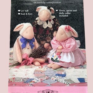 May include: A pattern for Lavender Lamb plush toys. The image shows three lambs, each with unique outfits, including a dress, apron, and doily collar. The pattern is 21 inches tall and is described as fast and easy to make.