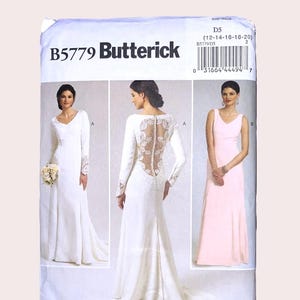 May include: A Butterick B5779 sewing pattern envelope for sizes 12-14-16-18-20. The front displays three dress variations: a long-sleeved white gown with lace cuffs, a white gown with a lace back and button detail, and a sleeveless light pink gown.