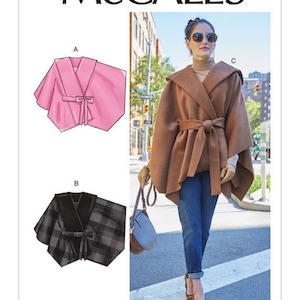 May include: A woman wearing a brown hooded cape with a tie belt, blue jeans, and leopard print heels. The image also shows illustrations of a pink cape and a black and gray plaid cape. The McCall's logo and pattern number M8029 are visible.