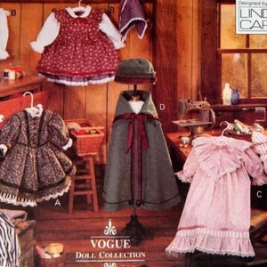May include: A selection of vintage doll clothes, including dresses, a cape, and trousers. The dresses feature floral patterns and lace trim. The cape is grey with a red ribbon. The Vogue Doll Collection logo is visible.