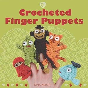 May include: A collection of colorful crocheted finger puppets, including a monkey, cat, fish, and other characters. The puppets are displayed on a hand, with the title "Crocheted Finger Puppets" in red letters on a green background. The author's name, Gina Alton, is also visible.