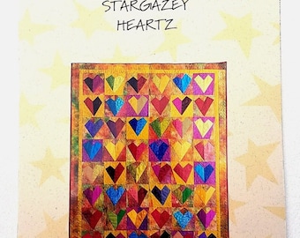 May include: A brochure for Stargazey Quilts featuring a colorful quilt design. The quilt is composed of numerous heart shapes in various colors, including red, blue, yellow, and purple. The brochure has text that reads "Stargazey Quilts presents Stargazey Heartz."