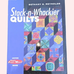 May include: A book titled "Stack-n-Whackier Quilts" by Bethany S. Reynolds. The cover features a blue background with colorful quilt block designs in red, yellow, green, and blue. The book is labeled as "Another Magic Stack 'n Whack Book."