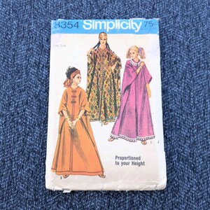 May include: Vintage Simplicity sewing pattern 8354 featuring illustrations of three different caftan designs. The pattern envelope is white with blue text and illustrations in shades of orange, green, and pink. The text "Proportioned to your Height" is visible.