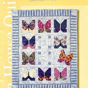May include: A quilt pattern titled "Butterfly's Break" featuring a grid of colorful butterfly designs. The quilt measures 53" x 65". The butterflies have various patterns and colors, set against a light blue background. The quilt is framed with a striped border.