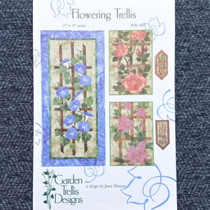 May include: A Flowering Trellis quilt pattern sheet by Janet Pittman featuring Garden Trellis Designs. The white paper displays illustrations of blue morning glories, pink roses, and pink clematis on wooden trellises, measuring 17 x 37 inches.