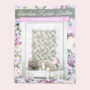 May include: A rectangular pattern booklet titled Garden Twist Quilts from In The Beginning fabrics. The cover features a floral border and a central image of a quilt with a green and white lattice design hanging above a white wicker desk.